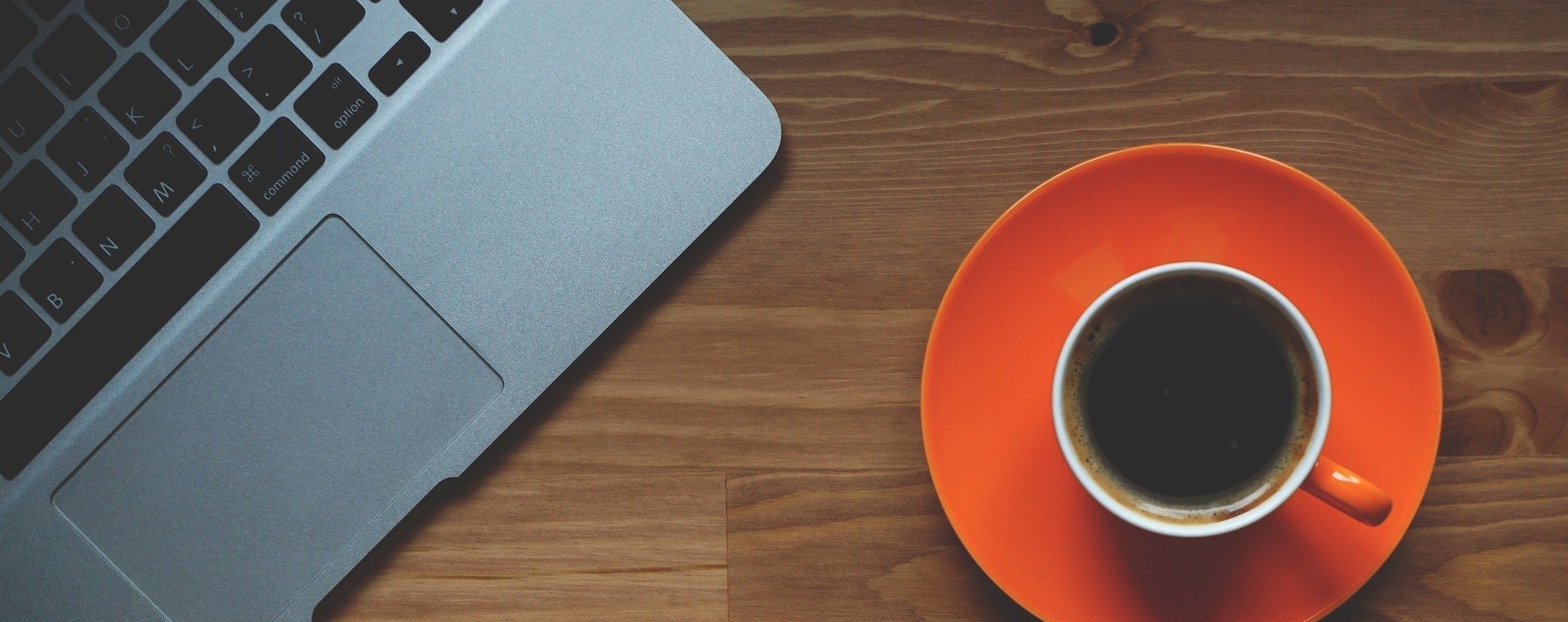 A coffee cup on a table next to a laptop
