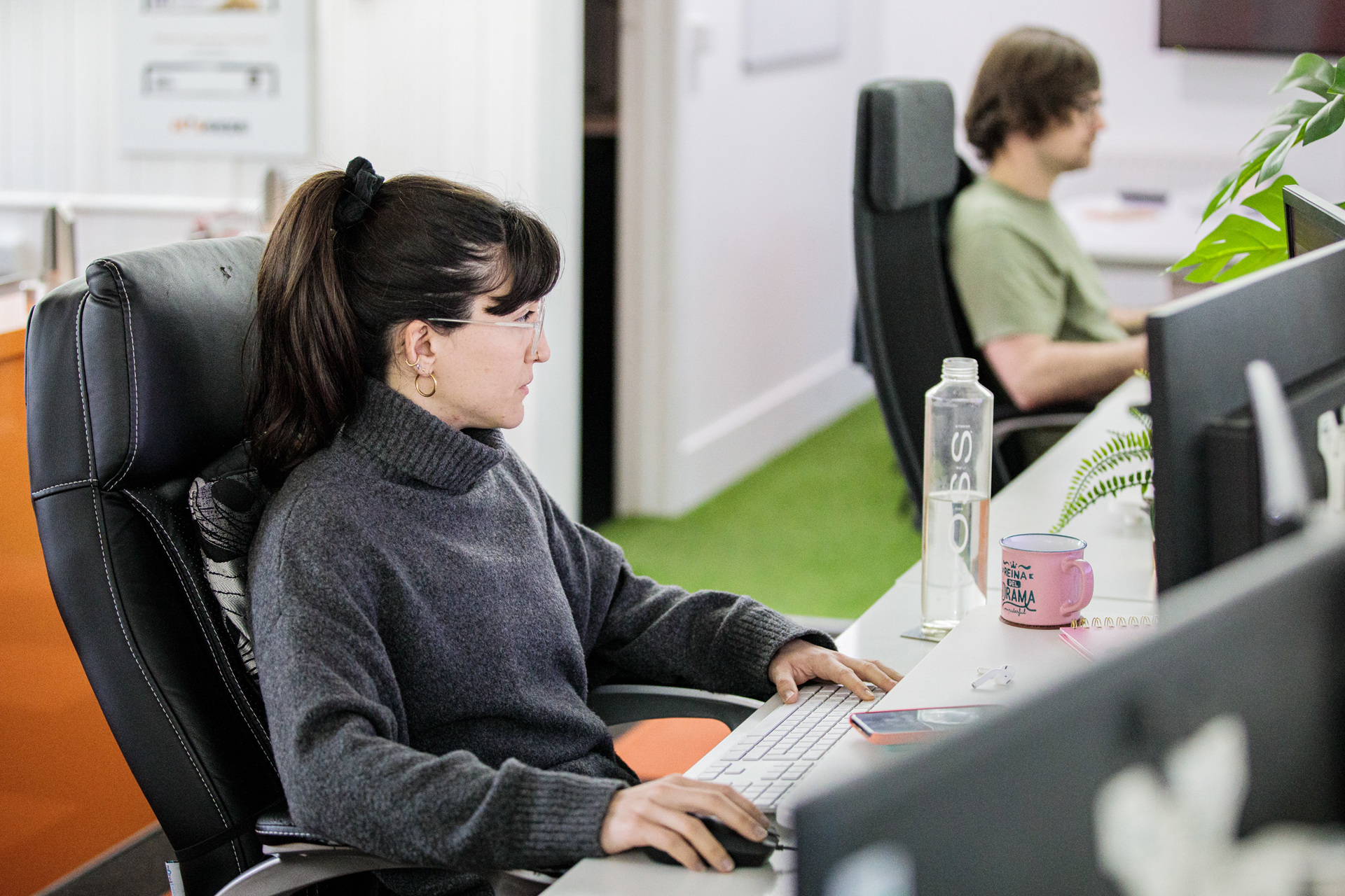 A website designer sat at her desk working on her desktop computer